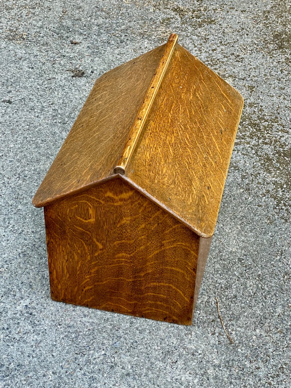 An antique Victorian warm brown oak dog kennel featuring a pitched roof, arched entrance aperture, and trefoil ventilation cutouts along the side. View IX