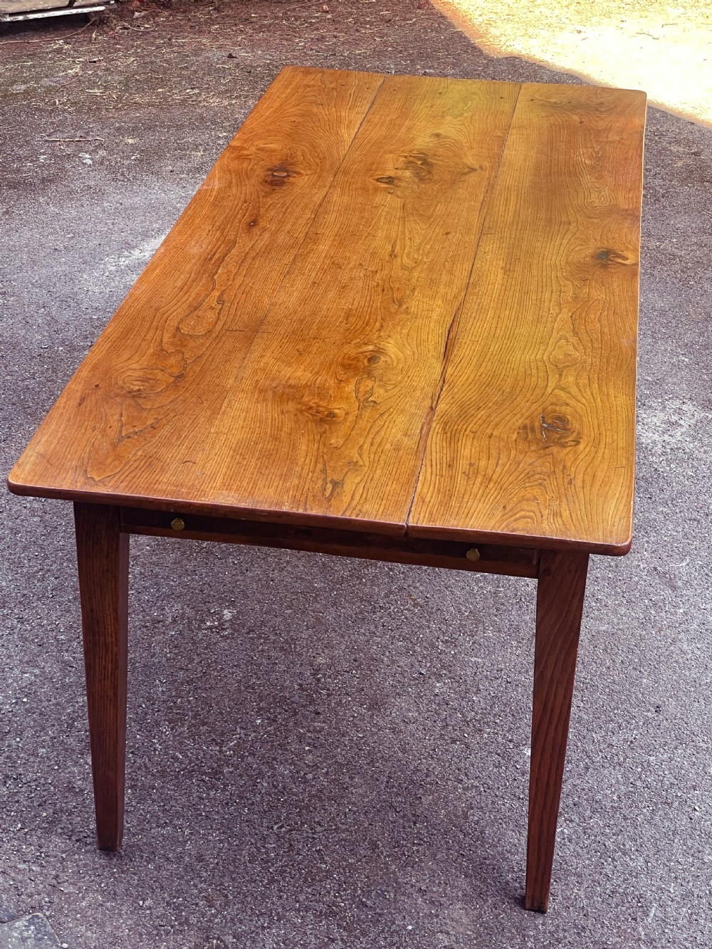 A long wooden refectory dining table constructed with a three-plank top and four square tapered legs. View V