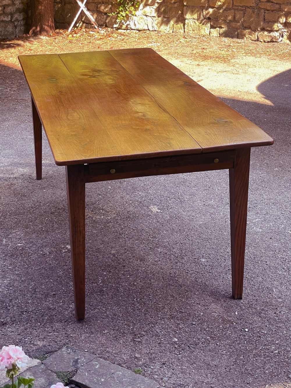 A long wooden refectory dining table constructed with a three-plank top and four square tapered legs. View VI
