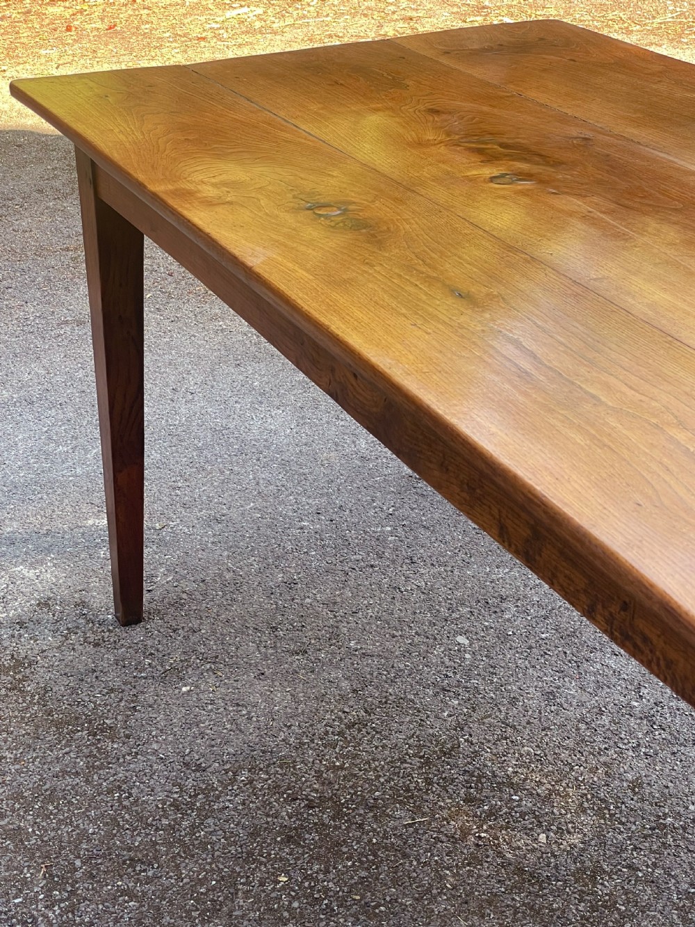 A long wooden refectory dining table constructed with a three-plank top and four square tapered legs. View VIII
