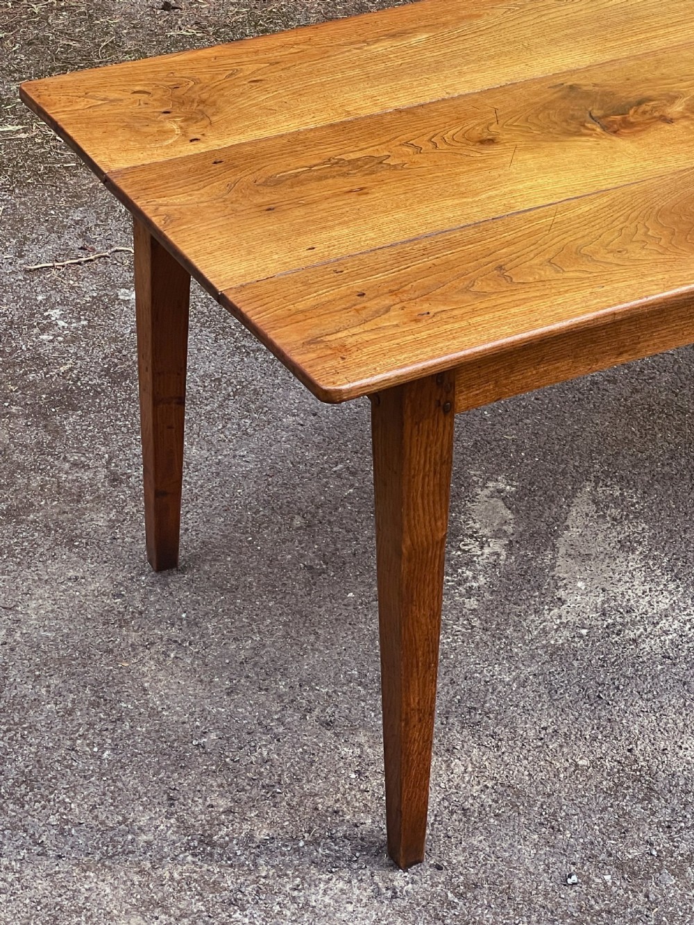 A long wooden refectory dining table constructed with a three-plank top and four square tapered legs. View X
