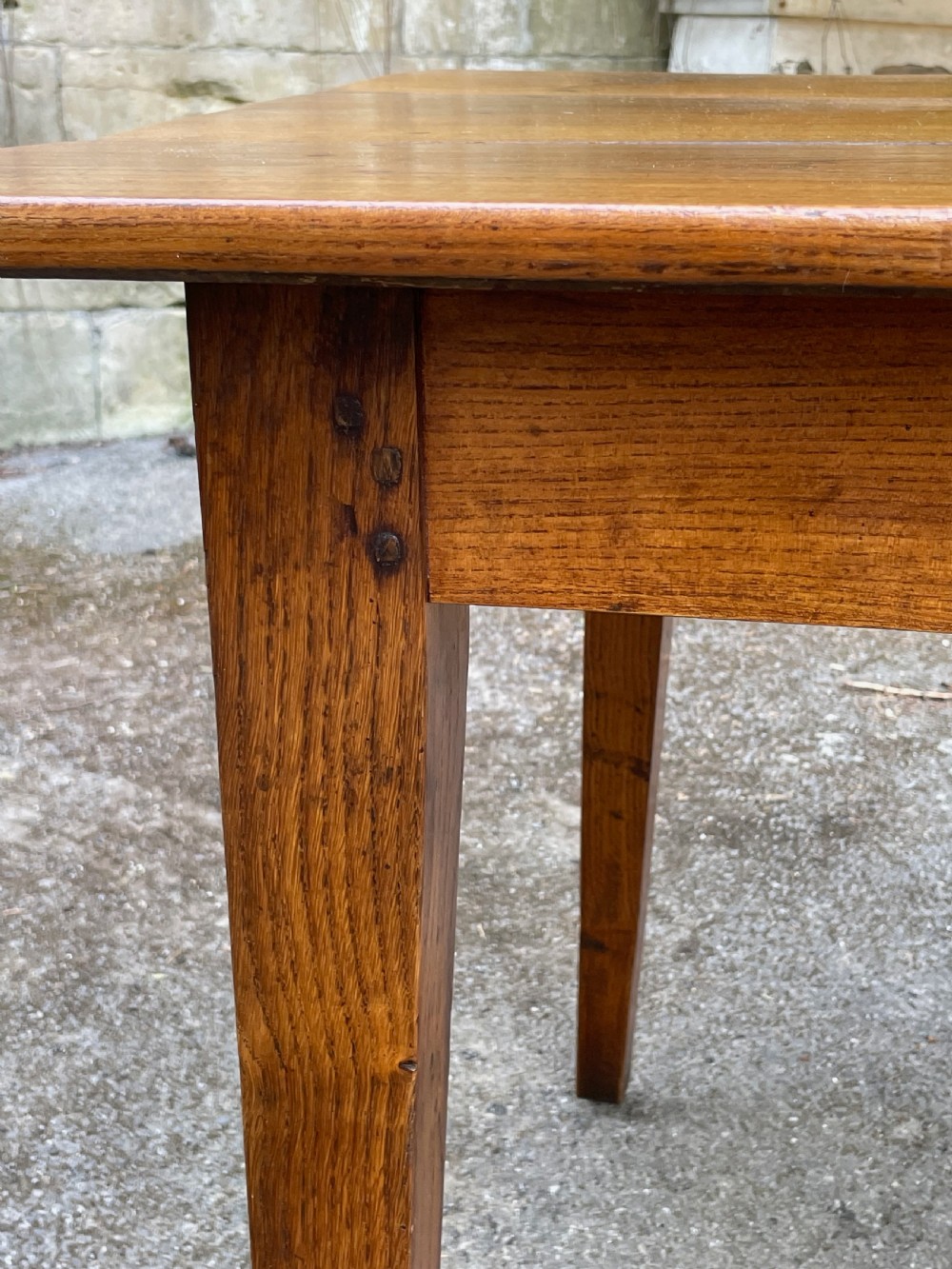 A long wooden refectory dining table constructed with a three-plank top and four square tapered legs. View XIII