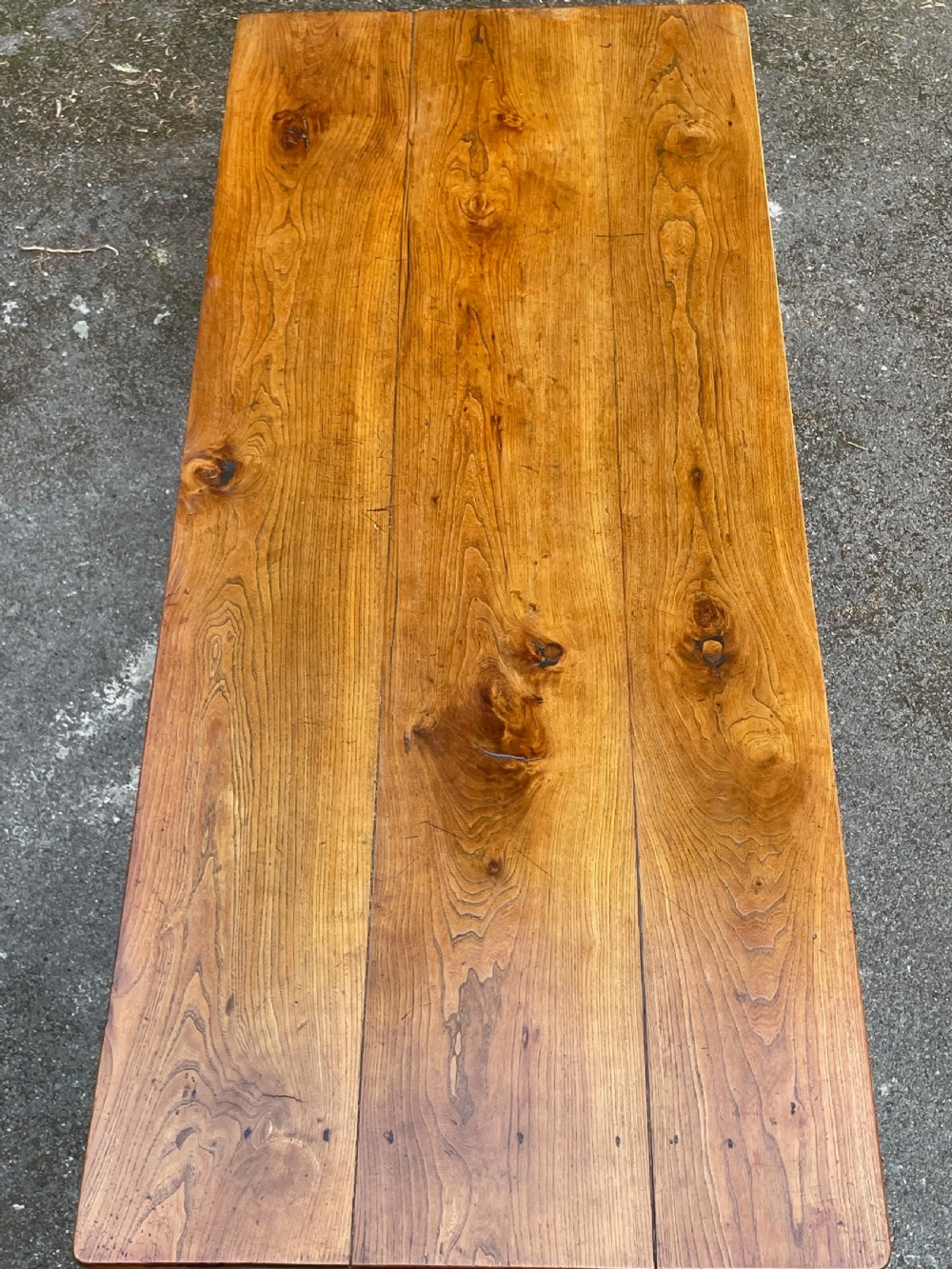 A long wooden refectory dining table constructed with a three-plank top and four square tapered legs. View XVI