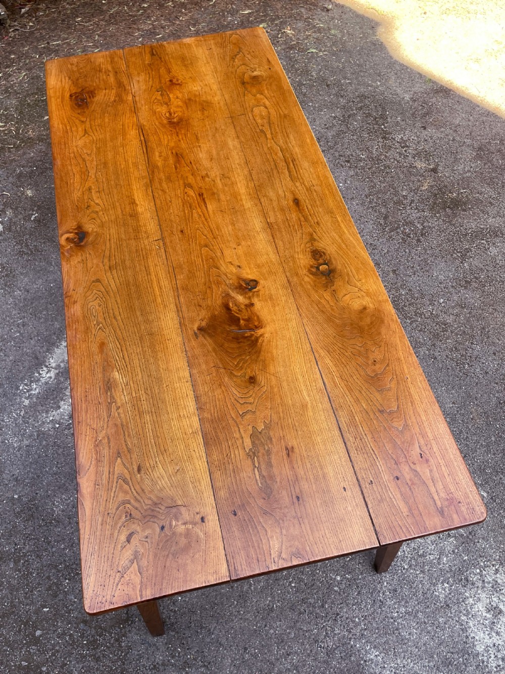 A long wooden refectory dining table constructed with a three-plank top and four square tapered legs. View XVII