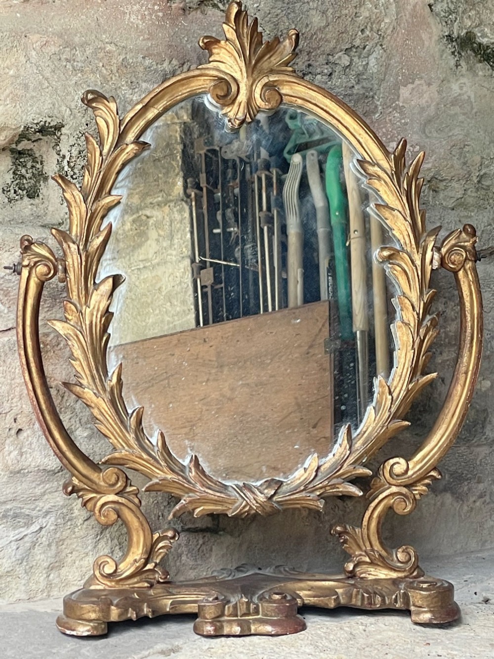 A carved giltwood toilet mirror with an oval pivoting mirror frame set on a decorative scrolling base. View IV