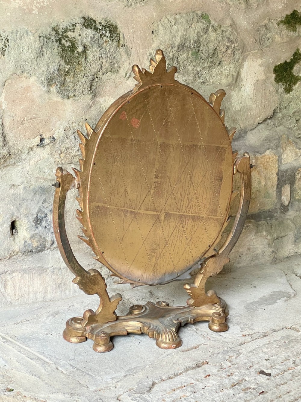 A carved giltwood toilet mirror with an oval pivoting mirror frame set on a decorative scrolling base. View VIII