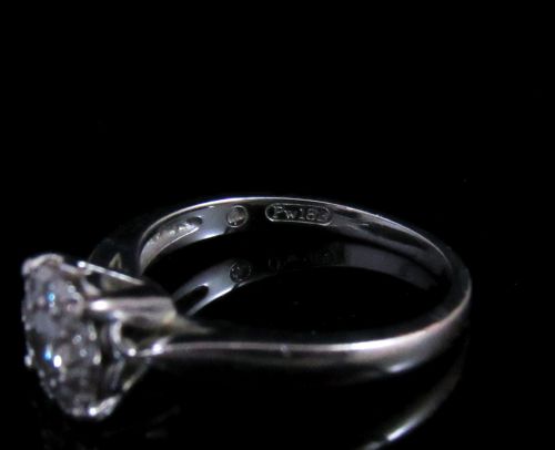 fig 2. An 18kt white gold ring featuring a raised round cluster setting set with multiple brilliant-cut diamonds.