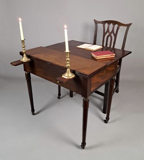 fig 4. A George III mahogany campaign table with a split hinged top, flame mahogany drawer front, brass collar mounts, turned tapering legs, and brass castors.