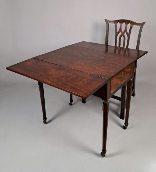fig 1. A George III mahogany campaign table with a split hinged top, flame mahogany drawer front, brass collar mounts, turned tapering legs, and brass castors.