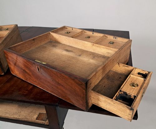 fig 3. A George III mahogany campaign table with a split hinged top, flame mahogany drawer front, brass collar mounts, turned tapering legs, and brass castors.