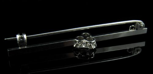 fig 2. An Art Deco 18ct white gold bar brooch featuring a central trefoil cluster of old-cut diamonds on a slender horizontal bar.