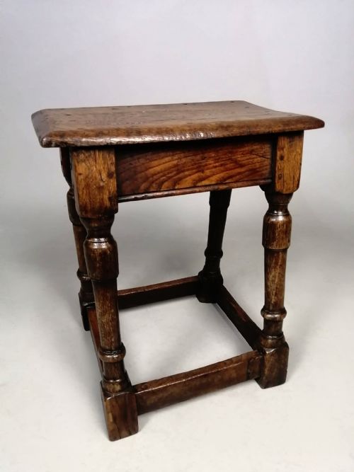 fig 2. An antique dark oak and elm joint stool featuring turned legs, peg joinery, a square stretcher base, and a rectangular timber seat.