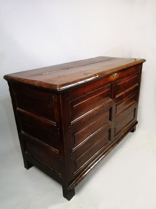 fig 3. A seventeenth-century dark oak coffer featuring six rectangular raised panels on the front facade and a central brass keyhole escutcheon.