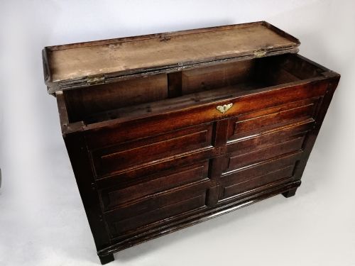fig 5. A seventeenth-century dark oak coffer featuring six rectangular raised panels on the front facade and a central brass keyhole escutcheon.