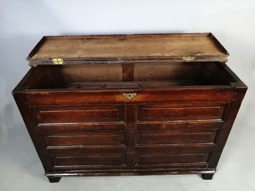 fig 6. A seventeenth-century dark oak coffer featuring six rectangular raised panels on the front facade and a central brass keyhole escutcheon.