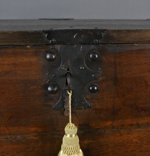 fig 3. A 17th-century dark oak strong box featuring a fall-front desk opening to reveal small internal drawers, resting on a turned stand with stretchers.