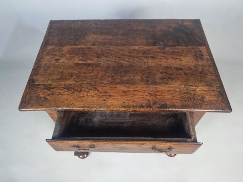 fig 3. A Queen Anne period oak and elm lowboy featuring a single drawer with brass drop handles, turned legs, and a curved X-frame stretcher.