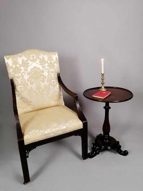 fig 1. A George II mahogany library chair upholstered in cream damask fabric featuring carved Chinese Chippendale fretwork on the legs and arms.