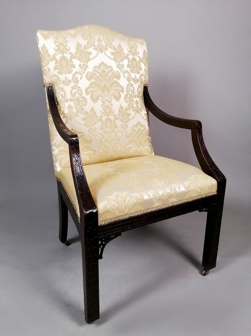 fig 2. A George II mahogany library chair upholstered in cream damask fabric featuring carved Chinese Chippendale fretwork on the legs and arms.