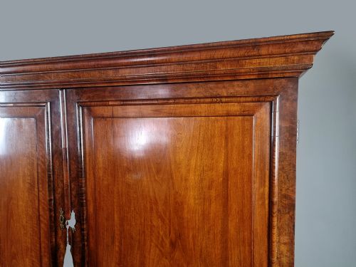 fig 1. A Queen Anne burr walnut press cupboard featuring a double-door upper section above six lower drawers with brass drop handles.