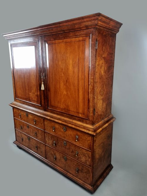 fig 2. A Queen Anne burr walnut press cupboard featuring a double-door upper section above six lower drawers with brass drop handles.