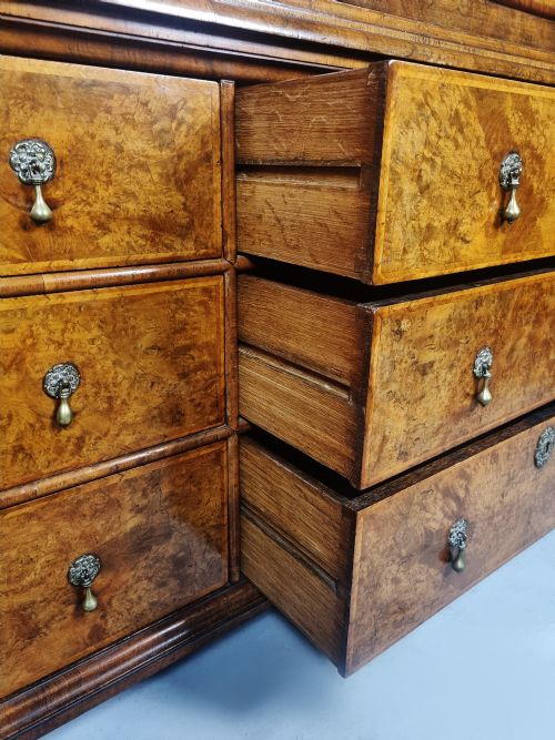fig 7. A Queen Anne burr walnut press cupboard featuring a double-door upper section above six lower drawers with brass drop handles.