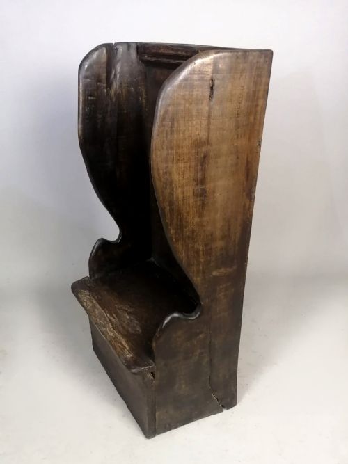 fig 1. A dark fruitwood childs lambing chair featuring a tall panelled back, enclosed wing sides, and a solid rectangular box base.