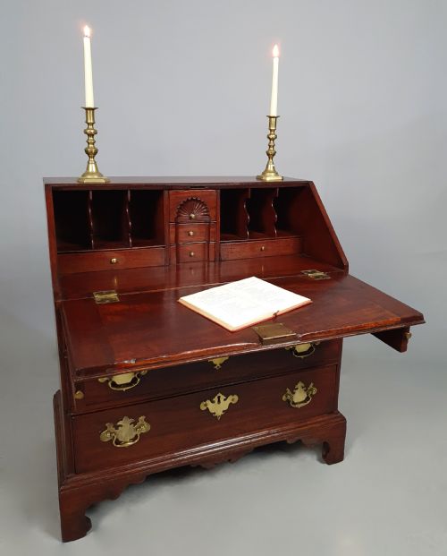 fig 2. An 18th-century George II slant-front writing bureau made of warm brown fruitwood with brass drop handles and bracket feet.