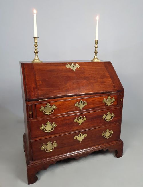 fig 3. An 18th-century George II slant-front writing bureau made of warm brown fruitwood with brass drop handles and bracket feet.