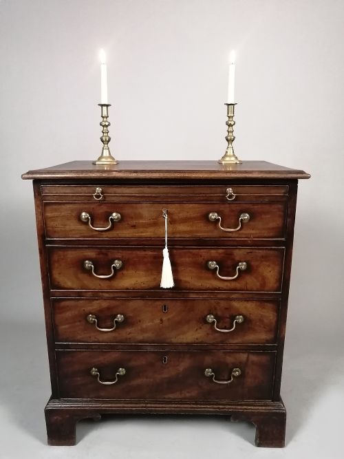 fig 5. A small George III Cuban mahogany bachelors chest featuring four graduated drawers, brass swan-neck handles, a brushing slide, and bracket feet.