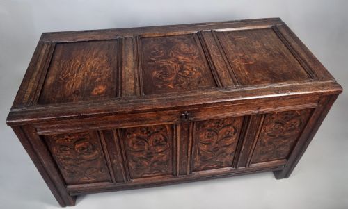 fig 4. A 17th-century dark oak coffer featuring four front panels with floral marquetry inlay and a panelled hinged top.