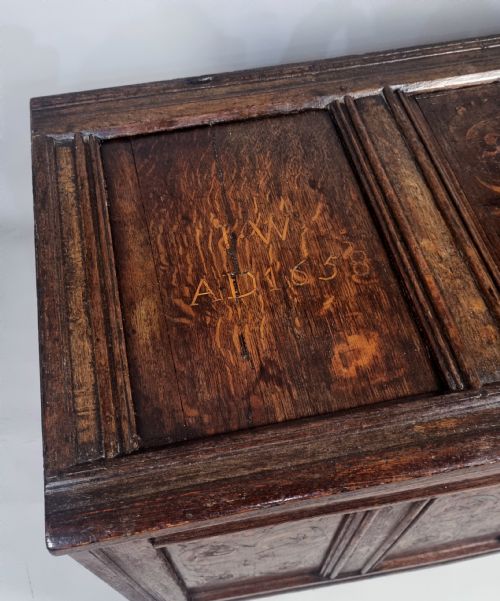 fig 5. A 17th-century dark oak coffer featuring four front panels with floral marquetry inlay and a panelled hinged top.