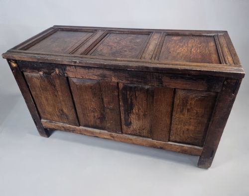 fig 7. A 17th-century dark oak coffer featuring four front panels with floral marquetry inlay and a panelled hinged top.