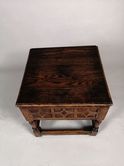 fig 2. A 17th-century dark oak box stool featuring a carved geometric frieze, turned legs, and lower stretchers.