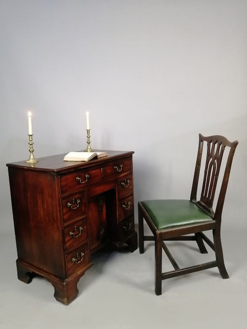 fig 1. A mid-18th century George II mahogany kneehole desk featuring a long top drawer over six side drawers and a central recessed cupboard on bracket feet.