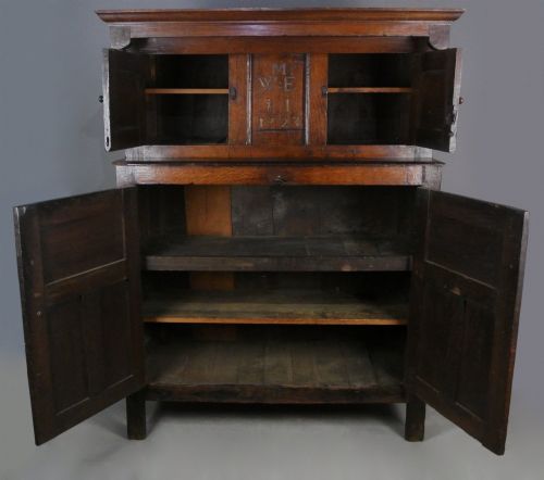 fig 4. An 18th-century dark oak court cupboard featuring a carved date of 1723, upper recessed cabinet with drop finials, and fielded lower door panels.