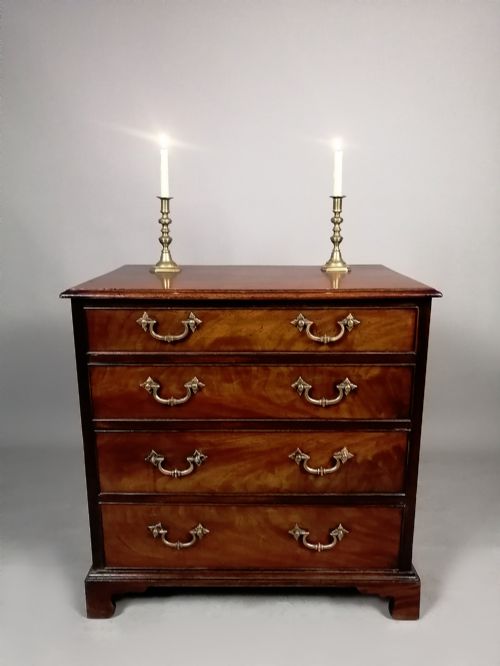 fig 3. A compact George III Cuban mahogany chest of drawers featuring four graduated drawers with brass swan-neck handles and bracket feet.