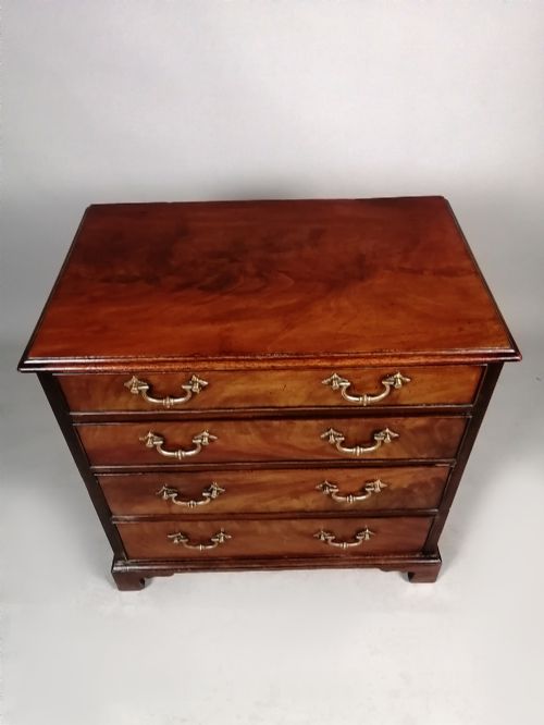 fig 4. A compact George III Cuban mahogany chest of drawers featuring four graduated drawers with brass swan-neck handles and bracket feet.