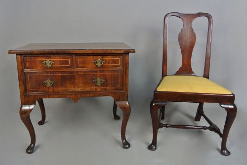 fig 1. A George I walnut lowboy table featuring three featherbanded drawers with brass handles, cabriole legs, pad feet, and a shaped apron.
