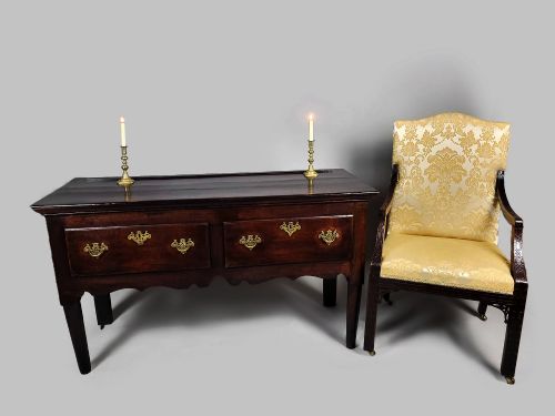 fig 1. A George III dark oak dresser base featuring two drawers with ornate brass handles and escutcheons, a shaped apron, and tapered legs.