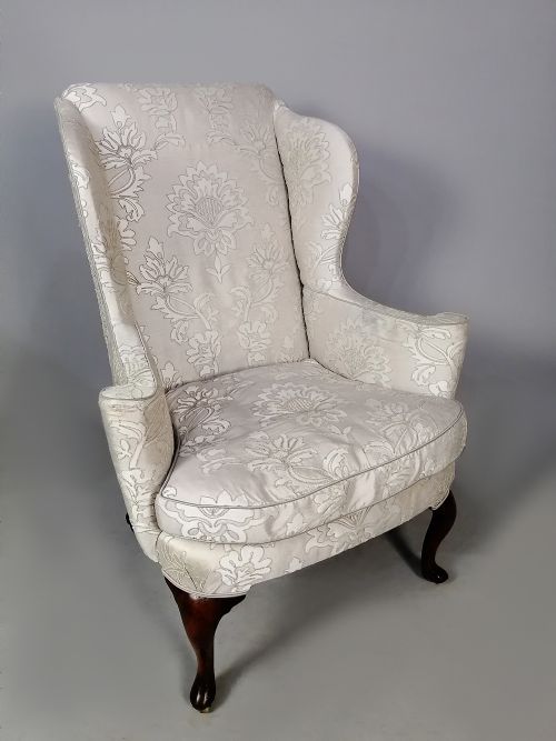 fig 2. A Victorian wingback armchair upholstered in light cream floral damask fabric with dark carved walnut cabriole legs.