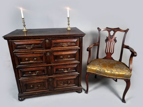 fig 1. A seventeenth-century dark oak chest of drawers featuring geometric mitred drawer panels, brass swing handles, and turned bun feet.