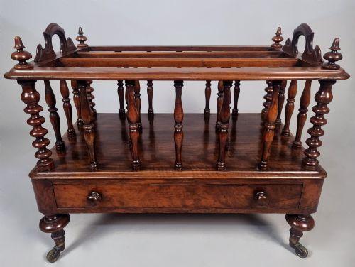 fig 3. A Victorian walnut Canterbury featuring vertical spindle dividers, a lower drawer base, carved side handles, and turned feet with brass castors.