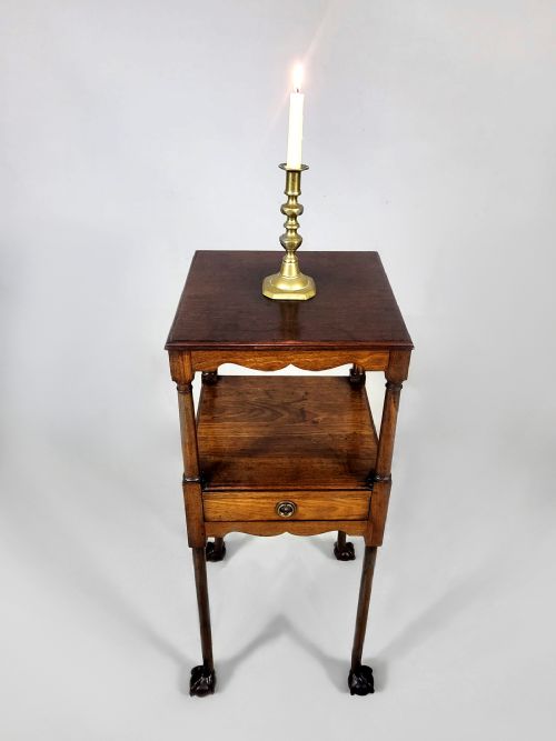 fig 1. An antique George III Cuban mahogany nightstand featuring tiered shelves, a central drawer, turned column supports, scalloped aprons, and carved claw and ball feet.