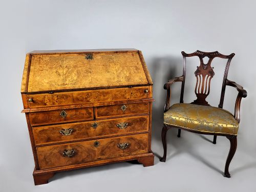 fig 1. An early 18th-century George I burr walnut bureau featuring a slant-front lid over graduating drawers with brass handles and bracket feet.
