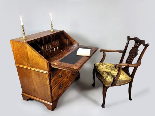 fig 2. An early 18th-century George I burr walnut bureau featuring a slant-front lid over graduating drawers with brass handles and bracket feet.