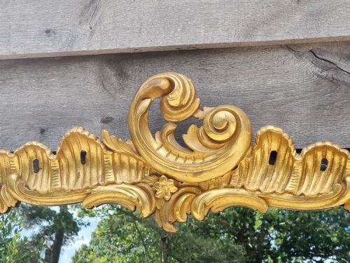 fig 1. A large 19th-century giltwood mirror featuring carved C-scroll cresting, acanthus leaf detailing, and a gilded frame surrounding a glass plate.