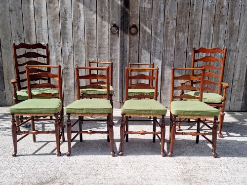 fig 1. A set of eight 19th-century wooden country dining chairs featuring woven rush seats with green seat pads, shaped horizontal back slats, and turned legs.