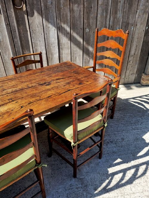 fig 3. A set of eight 19th-century wooden country dining chairs featuring woven rush seats with green seat pads, shaped horizontal back slats, and turned legs.