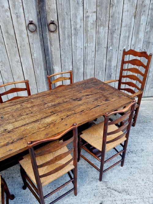 fig 4. A set of eight 19th-century wooden country dining chairs featuring woven rush seats with green seat pads, shaped horizontal back slats, and turned legs.